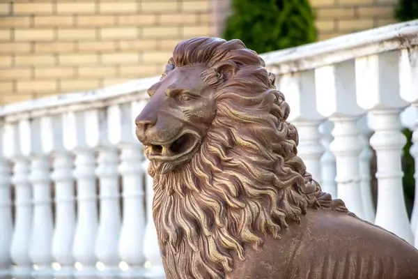 Beyaz balyaların yanında duran kendine özgü yelesi olan bir aslan heykelinin yakın çekimi.