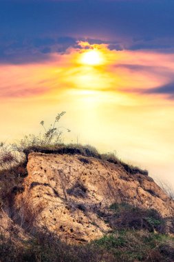 Gün batımı bulutlu gökyüzü kil tepe bitki örtüsü dramatik doğa manzarası