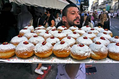 JERUSALEM, ISR - 11 Nisan 2022: İsrailli adam İsrail 'in Machane Yehuda Market Kudüs kentindeki Yahudi bayramı bayramı için pişirilen taze Sufganiyot (İsrail çörekleri) dolu bir fırın tepsisi taşıyor.