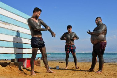 Ölü Deniz - 10 Kasım 2022: Kendilerini Ölü Deniz çamuru ile kaplayan İsrailli bir grup insan. Çamur nemi geri getirmeye ve semptomları azaltmaya, kuru, pürüzlü, tahriş olmuş cilt, sivilce, egzama ve sedef hastalığını yatıştırmaya yardımcı oluyor.