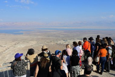 MASADA, ISR - NOV 10 2022: Ölü deniz manzarasına bakan bir grup turist ve İsrail 'deki Masada antik doğal kalesinden Ürdün..