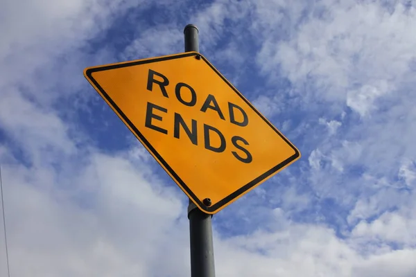 Road ends traffic sign under dramatic blue sky with clouds.