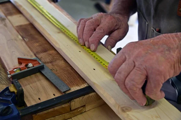 Zbliżenie Rąk Cieśli Mierzących Drewnianą Deskę Taśmą Pomiarową — Zdjęcie stockowe
