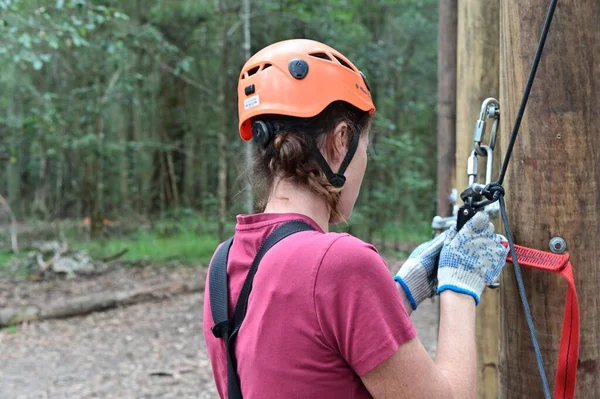 一个成年妇女在爬树过程中利用自己的树桩进行攀爬 妇女风险和挑战概念 真正的人复制空间 — 图库照片