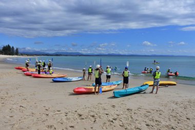 BYRON BAY, NSW - APR 02 2023: Büyük bir Avustralya grubu Byron Bay plajında kano kullanmayı öğreniyor. Kano, insan gücüyle çalışan ve en az 4000 yıldır kullanılan küçük bir su gemisidir..