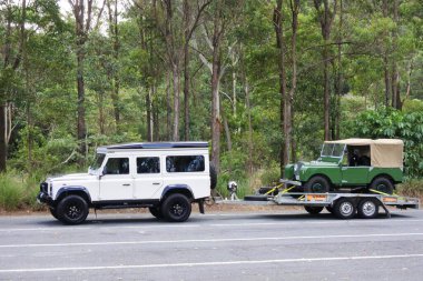 BYRON BAY, NSW - APR 02 2023: Defender 110 300tdi towing the first Land Rover R01.Land Rover Defender  British made vehicles gained a worldwide reputation for ruggedness and versatility. clipart