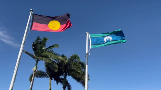 澳大利亚原住民的澳大利亚国旗和托雷斯海峡群岛的国旗在蓝蓝的热带天空背景下飘扬 — 图库视频影像