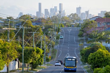 BRISBANE - NOV 13 2023: Brisbane City Skyline 'a karşı bir yolda kamu otobüsü. Brisbane' nin büyük bir otobüs hızlı ulaşım ağı var, Brisbane otobüs yolu ağı 400 'den fazla rota ve 10 binden fazla istasyondan oluşuyor..