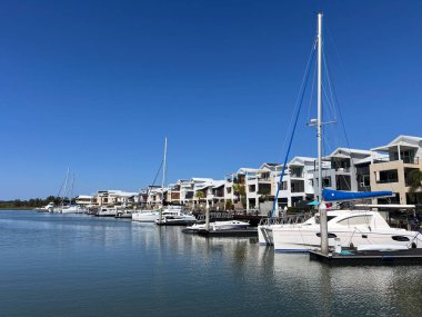 COOMERA, QLD - SEP 8 2024: Avustralya 'nın Queensland kentindeki Coomera Nehri' nin kıyısındaki Coomera Waters Marina lüks yerleşim bölgesinde yelkenli tekneleri demirledi.