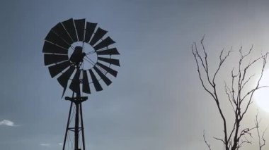 Queensland, Avustralya 'da bir çiftlikte su pompalayan rüzgar pompasının silueti. 