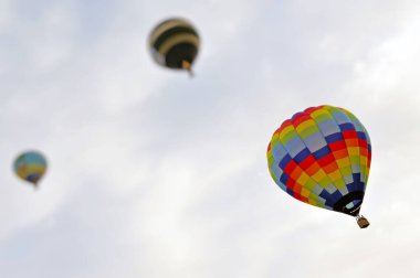Havada süzülen üç sıcak hava balonunun alçak açılı görüntüsü.