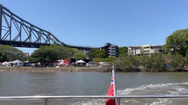 Brisbane, Avustralya 'daki Story Bridge kantilever listesindeki köprüden uzaklaşan bir teknenin arka görüntüsü..