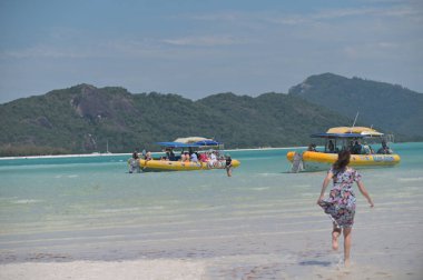 Whitsunday Adaları 'na giden küçük bir tekneye binen yelkenli yolcuları, Whitsunday Adası' ndaki The Great Barrier Reef ve Whitehaven plajlarına doğru popüler bir durak..