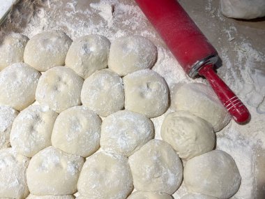 Fırın tezgahının üstünde rulo ekmek hamuru ve merdane..