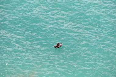 Küçük bir balıkçı teknesinde denizde balık tutan tanınmayan bir balıkçının hava aracı görüntüsü..