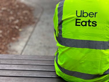 SYDNEY - 13 Ocak 2025: Sydney, Yeni Güney Galler 'deki bir bankta dinlenen Uber Eats kuryesi. 2021 itibariyle 45 ülkede 6 binden fazla şehirde Uber yemek yiyor..