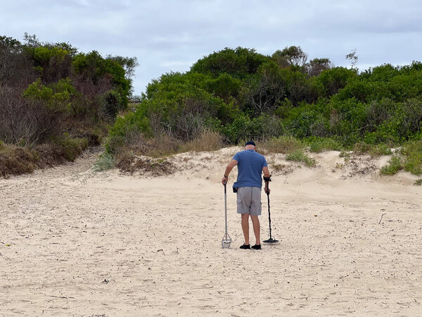 SYDNEY - JAN 04 2025:Person using metal detector on sandy beach.The global hobby metal detectors market size was valued at approximately USD 2.1 billion in 2023 and is projected to grow bigger.