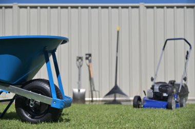 Bahçıvan aletleri yeşil çimlerin arka bahçesinin yanındaki ev çitlerine yaslanıyor