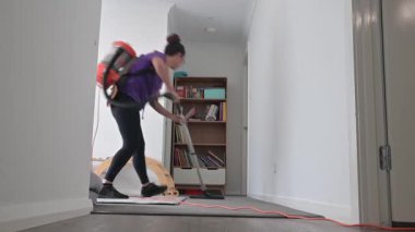 Profesyonel ev temizleyicisi (35-45 yaş) elektrikli süpürge kullanarak halının tozunu temizliyor..