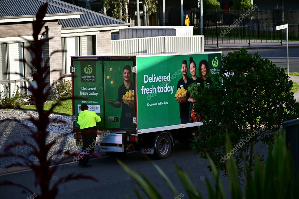 PORT MACQUARIE - JNE 05 2025: Woolworth grocery delivery driver and truck.Woolworths home delivery fleet is currently made up of 1,200 trucks and growing