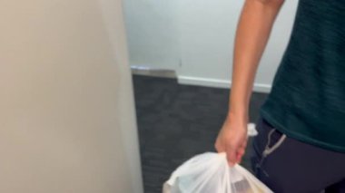Tanınmayan bir kadın çöp torbasını çöp kanalına atıyor.