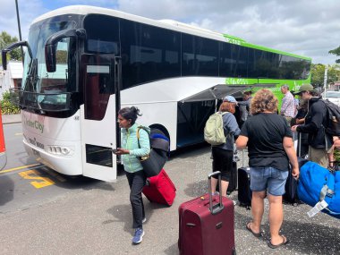 KERIKERI, NZL - Şubat 02 2025: Şehirlerarası otobüse binen turistler. InterCity, Yeni Zelanda 'nın günlük 600 kasaba ve halka hizmet veren tek şehirler arası otobüs ağı..