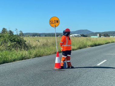 Tanımlanamayan yol işçisi, kırsal kesimdeki bir trafik işaretinin yanında duruyor..