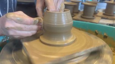Kadın elleri çömlek çarkında kil yaratıyor ve şekillendiriyor