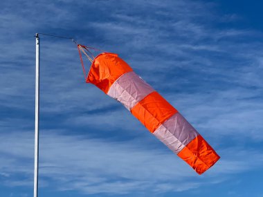 Havalimanı Turuncu ve Beyaz Rüzgâr Çorapları mavi gökyüzünde bulutlarla esiyor.