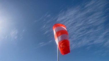 Havalimanı Turuncu ve Beyaz Rüzgâr Çorapları mavi gökyüzünde bulutlarla esiyor.