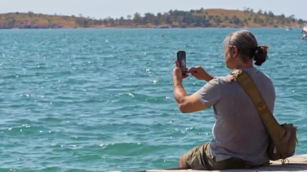 Resenär Man Fånga Ocean View Med Mobiltelefon Sitter Trä Pier — Stockvideo