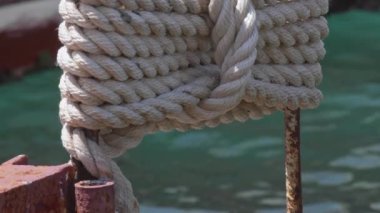 Deniz kenarındaki görüntüde düğümlenmiş ve paketlenmiş tekne halatı.