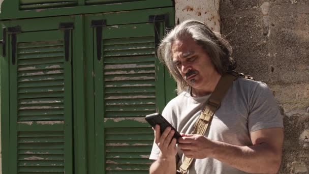 携帯電話のフッテージでストリートで彼の恋人と話している中年の男 — ストック動画