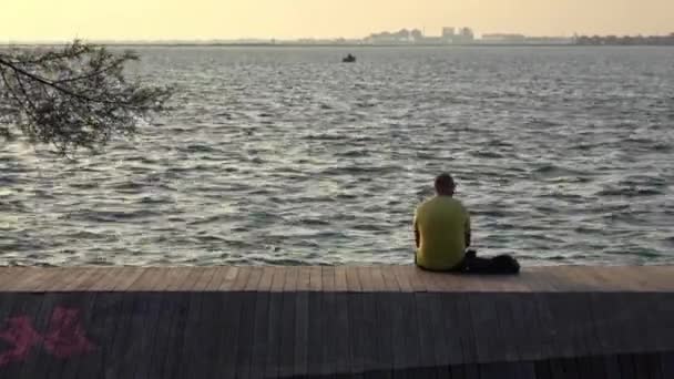 海を見下ろすビーチに座っている孤独な中年男性 — ストック動画