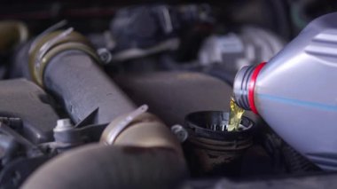 Tamir atölyesindeki Araç Periyodik Bakım sırasında Motoru Yeni Sentetik Yağ ile Doldurmak.