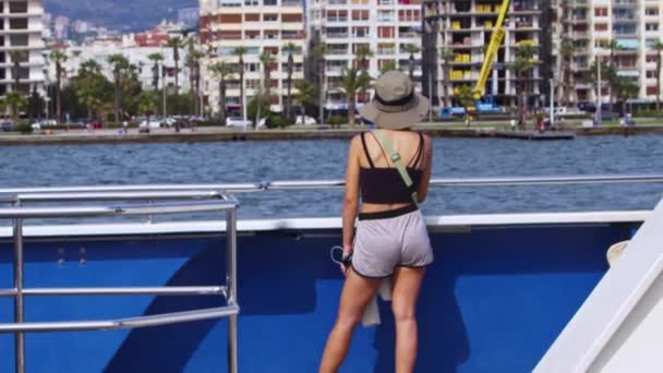 帽女游客在船上观看海滨城市的景象 — 图库视频影像