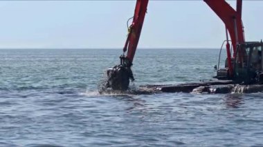 Kazıcı, deniz görüntülerindeki çöpleri ve lağım çukurlarını temizliyor..
