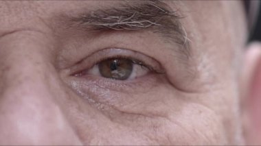 Yaşlı adam kameraya bakarak gözlerini kapatıyor..