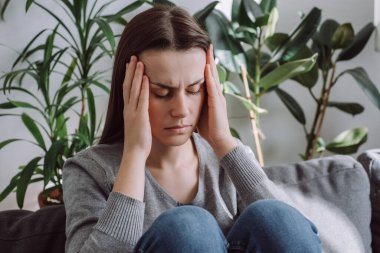 Üzgün genç kız koltukta oturuyor. Güçlü baş ağrısı, migren, üzgün yorgun, yorgun, yorgun, beyaz kadın gergin gerginlik ve stresten sonra uyumaya çalışıyor. Somnolence kavramı