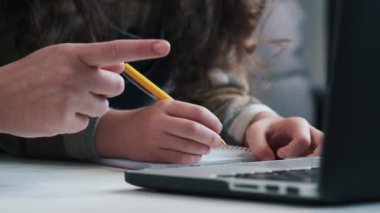 Çocuk ellerinin dizüstü bilgisayardan öğrendiği bir not defterine bir şeyler yazmasını, annesinin küçük kızına evde masa başında otururken ödevlerinde yardım etmesini. E-öğrenme kavramı