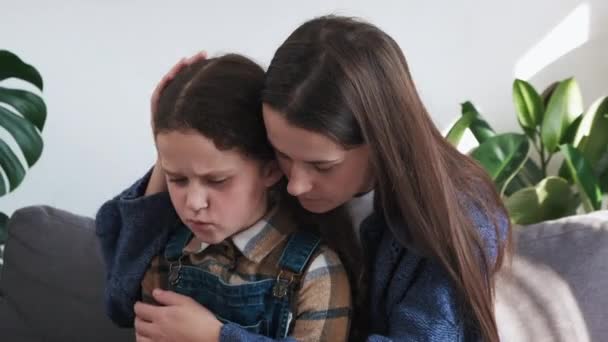 Zbliżenie Opiekuńczej Młodej Matki Przytulającej Uspokajającej Zdenerwowanej Córeczki Siedzącej Kanapie — Wideo stockowe