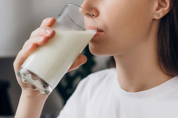 自宅で強い骨のためのカルシウムと若いブルネットの女性の飲料牛乳を撮影作物 ガラス上の豆乳を保持する女性は栄養の健康寿命でお楽しみください 天然乳とウェルネス フレッシュコンセプト — ストック写真