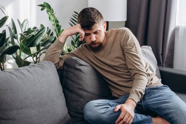 Düşünceli erkek sorun ya da sorun üzerinde kafa yoruyor. Kafkasyalı mutsuz bir adam kanepede oturup sorunların çözümünü düşünüyor. Düşüncelere odaklanmış genç bir adam bir şeyler düşünmeye karar veriyor.