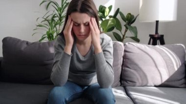 Somnolence konsepti. Üzgün genç bayan koltukta oturuyor güçlü baş ağrısı, migren, üzgün uykulu, yorgun esmer kadın sinirsel gerilim ve stresten sonra uyumaya çalışıyor.