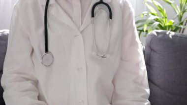 Steteskoplu beyaz önlüklü profesyonel doktor kadın eczacının elinde küçük pembe hapla hastanede rahat bir kanepede otururken, sağlık, sigorta, sağlık ve önleme konsepti.