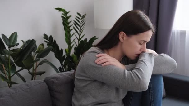 忧心忡忡的年轻女人哭泣 独自坐在沙发上 思考个人问题 与男朋友分手或离婚 需要心理帮助 感到孤独和沮丧 — 图库视频影像
