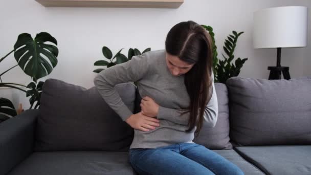 胃の痛みに苦しむ不健康な若い原因アジアの女性 腹を抱えて腹部の月経痛や腸や消化不良の問題を感じているブルネットの女の子のクローズアップ 食中毒の概念 — ストック動画