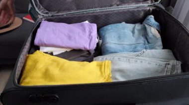Evde kadın eli bavulları düzgünce topluyor ve fermuarını çekiyor. Sıralama ve bagaj paketleme için giysi yığını. Tatile hazırım. Seyahat blogu temel gereksinimleri, yolculuk gezisi gezintisi yaşam tarzı