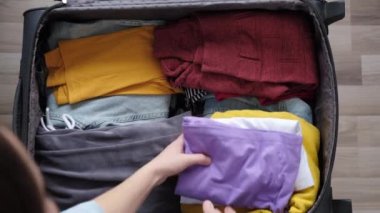 Gezgin genç kızın bavulunu düzgünce hazırlayıp tatil ya da gezi için düzenlediği yakın plan. Sıralama ve bagaj paketleme için giysi yığını. Seyahat blogcusunun temel ihtiyaçları, seyahat tutkusu ve yaşam tarzı konsepti