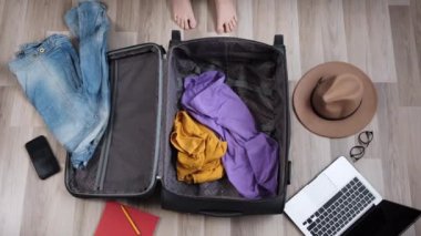 Genç bir bayanın manzarası bavulunu hazırlıyor. Tatil ya da tatil için hazırlanıyor. Giysileri ve eşyaları gardıroptan çantaya at. Seyahatten önce karmaşa ve kaos. Seyahat yaşam tarzı konsepti